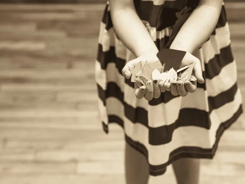 A child's cupped hands holding paper cut-outs